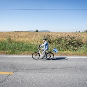 Un homme en vélo devant une terre agricole de Saint-Basile-le-Grand.