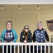 Trois femmes debout sur une galerie : Judy Daly, Tina Rennau et Jeb Bouchard.