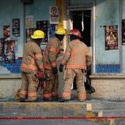 Trois pompiers observent à travers la porte d'un bâtiment.