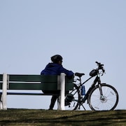 Un cycliste au repos assis sur un banc public.
