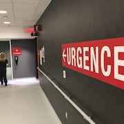 Des employés circulent dans un corridor où il est inscrit «urgence».