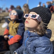 Un garçon regarde le ciel avec des lunettes de protection.