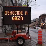 Un panneau afficheur sur remorque de la Ville de Québec installé en bordure de la rue Saint-Jean affiche les messages « CANADA COMPLICE » ET « GENOCIDE A GAZA ». 