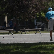 Un homme joue à la pétanque dans un parc à Montréal, par temps ensoleillé, le 24 juin 2025.