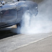Le frottement du pneu arrière d'une voiture sur l'asphalte crée de la fumée.