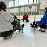 Des joueurs de parahockey en cercle sur une patinoire.