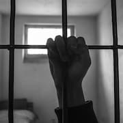 La main d'un détenu agrippée aux barreaux de sa cellule.