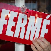 Une enseigne «fermé» dans la porte d'un commerce.