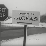 Dans un paysage d'hiver on voit deux panneaux.  Un signale un arrêt sur la route et l'autre le Congrès des jeunes scientifiques de l'Acfas tenu en novembre 1963. 