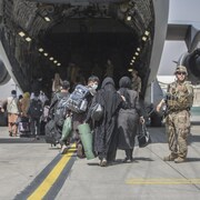 Des réfugiés embarquent par l'arrière d'un avion.