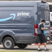 Un livreur de la compagnie Amazon à côté de son camion. 