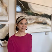 Angie Arsenault devant un mur où sont accrochés des tableaux.