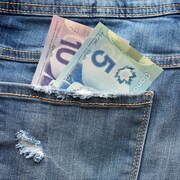 Gros plan sur la poche arrière d'un jeans contenant un billet de 10 $ et de 5 $ canadien. 