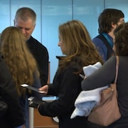 Des voyageurs montrent leurs passeports à un douanier à l'aéroport de Montréal