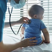 Une pédiatre examine un bébé avec un stéthoscope dans la salle médicale d'un hôpital.