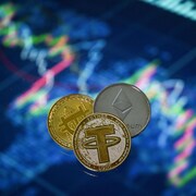 Trois jetons arborant les logos de certaines cryptomonnaies sont jointes ensemble.