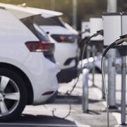 Un stationnement avec des voitures électriques branchées à des bornes de recharge.