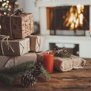 Une pile de cadeaux de Noël sur une table en bois devant une décoration de Noël.