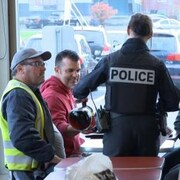 Une policière sert du café à des clients attablés.