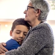 Un jeune garçon se fait prendre dans les bras de sa grand-mère.