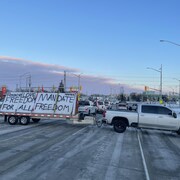 Une camionnette transportant une affiche en opposition à la vaccination obligatoire bloque la route. 