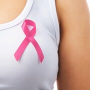 Un roban rose porté à la poitrine sur une camisole blanche.