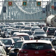 Plusieurs véhicules sont pris dans la congestion routière du pont Jacques-Cartier, à l'heure de pointe matinale à Montréal, alors qu'on voit les feux de circulation signalant les voies ouvertes et fermées dans les deux sens.