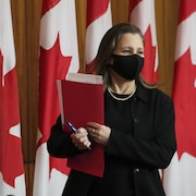 Chrystia Freeland tient des documents dans ses mains. 