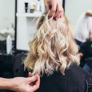 Un styliste place des cheveux d'une cliente dans son salon de coiffure.