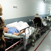 Des patients sur des lits d'hôpitaux dans un couloir.