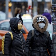 Des passants dans la rue à Toronto portant un masque.