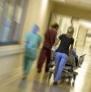 Des infirmières poussent une civière dans un couloir d'hôpital. 
