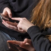 Plan rapproché des mains de deux adolescentes avec leur téléphone cellulaire entre les mains. 
