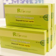 Des boîtes de tests rapides de dépistage empilées et présentées sur un comptoir. 