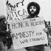 Un manifestant tient une pancarte avec l'inscription Honor for resisters. Amnesty for war criminals.
