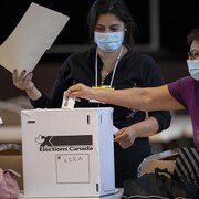 Une femme dépose son vote dans une boîte en carton.