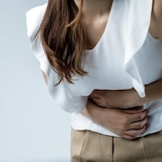 Une femme se tient l'abdomen en raison de douleurs.