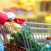 Femme poussant un panier d'épicerie.