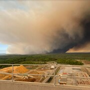 Un incendie de forêt brûle à l'horizon non loin du site d'une usine qui transforme du bois en pâte à papier. 