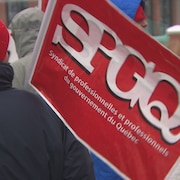 Des grévistes avec un drapeau frappé du logo du Syndicat de professionnelles et professionnels du gouvernement du Québec.