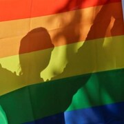 Drapeau au couleurs de LGBT et une personne en ombre chinoise