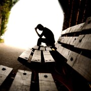 Une personne d'apparence déprimée est assise sur un banc à l'orée d'un tunnel.