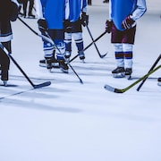 Les patins et les bâtons de jeunes joueurs de hockey sur une patinoire.