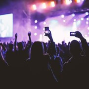 Des gens dans une foule tenant un téléphone intelligent devant un concert.