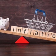 Un cochon tirelire est sur une balançoire avec un panier d'épicerie et le mot inflation.