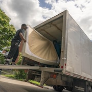 Un homme déplace un matelas dans un camion de déménagement.
