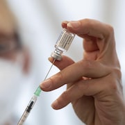 Gros plan sur une personne qui remplit une seringue à partir d'une fiole du vaccin contre la COVID-19.