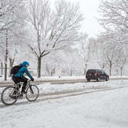 Une personne roule à vélo pendant une tempête de neige à Montréal.