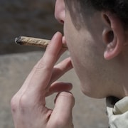 Un homme fume un joint de cannabis.