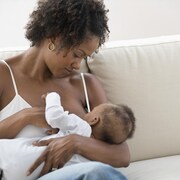 Une mère allaite son enfant sur un sofa.